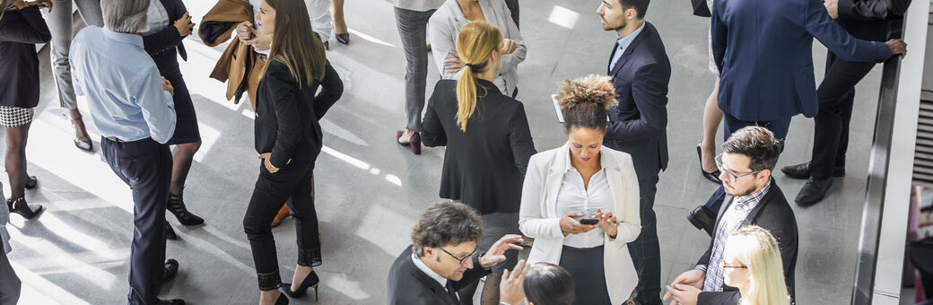Several individuals dressed in business professional attire networking and interacting