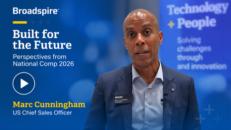 A speaker at a conference, identified as Marc Cunningham, discusses future perspectives for National Comp 2026, against a tech-themed backdrop
