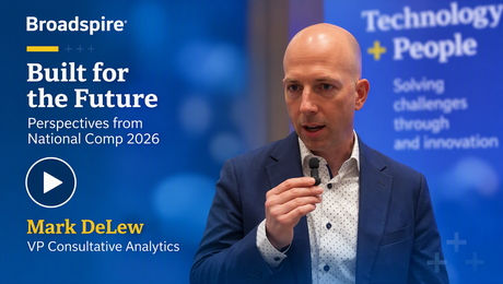A speaker in a blue blazer holds a microphone, discussing the theme "Built for the Future" at an event