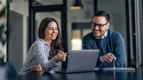 Two people working around a laptop computer.