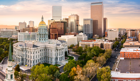 Aerial view of Denver's skyline at sunset, featuring the Colorado State Capitol building and modern skyscrapers