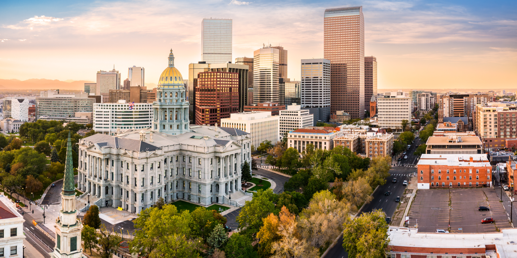 Aerial view of Denver's skyline at sunset, featuring the Colorado State Capitol building and modern skyscrapers