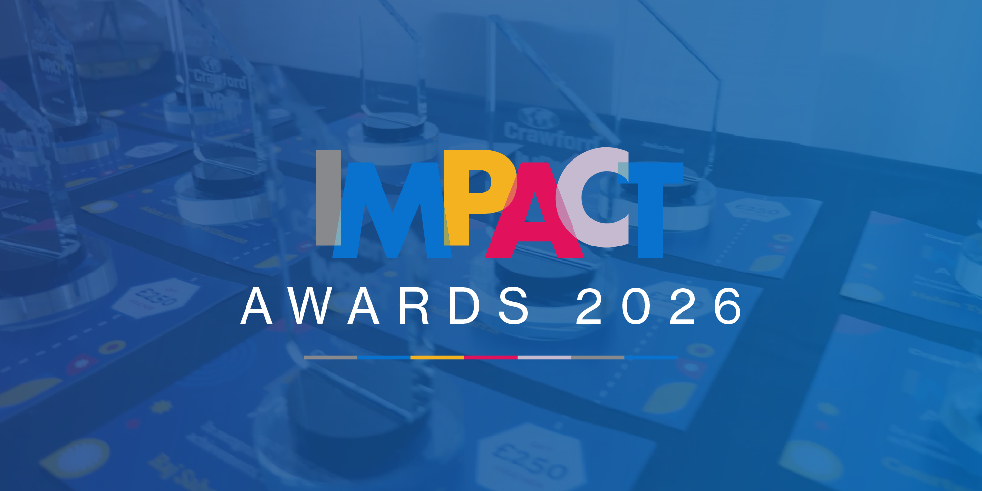 A display of awards with clear glass trophies and a colorful "IMPACT Awards 2026" logo in the foreground