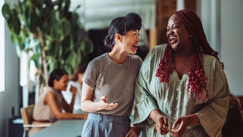Two women laughing together in an office setting