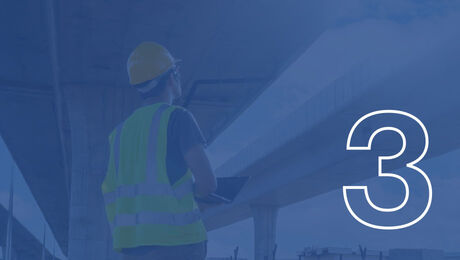 A person wearing a hard hat and reflective vest stands under a concrete structure, holding a laptop, with a large number "3" overlaying the image