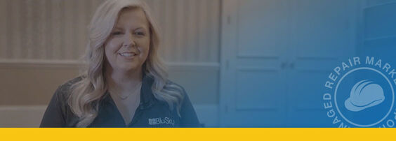 A person with long blonde hair smiles while wearing a logoed shirt, set against a softly blurred background