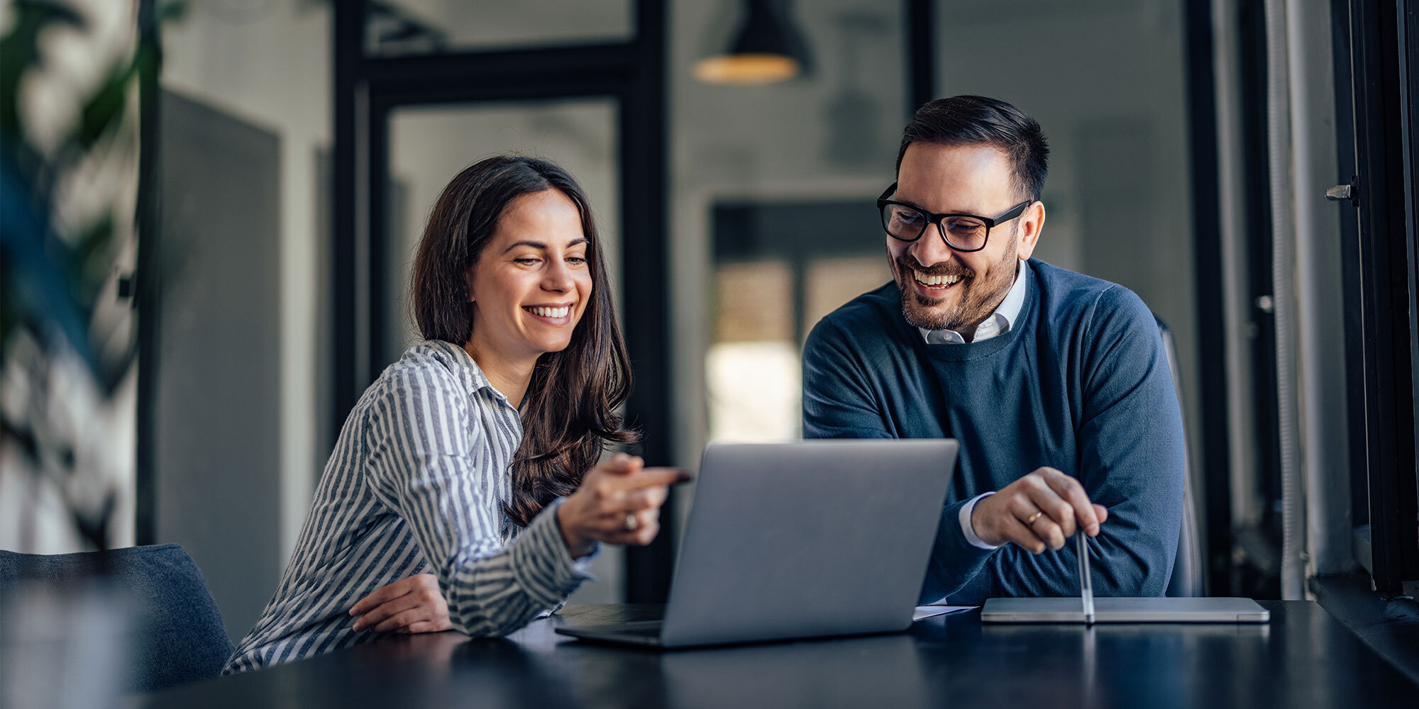 Two people working around a laptop computer.